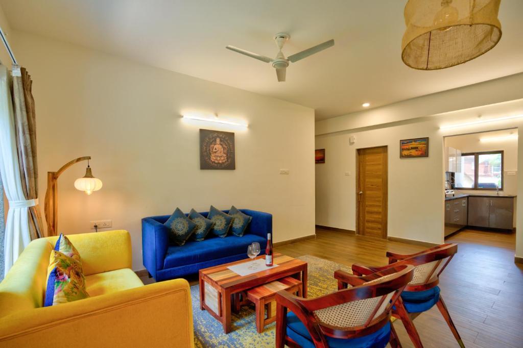 ein Wohnzimmer mit einem blauen Sofa und Stühlen in der Unterkunft Luxury 2BHK Apartment Near Candolim in Nerul
