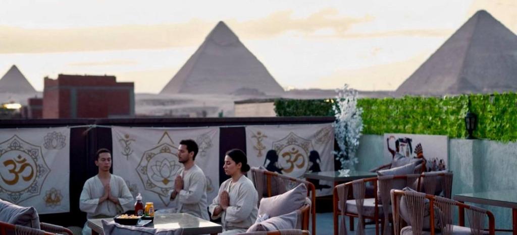 a group of people sitting at tables on a roof at majjesticc INN pyramids view in Cairo