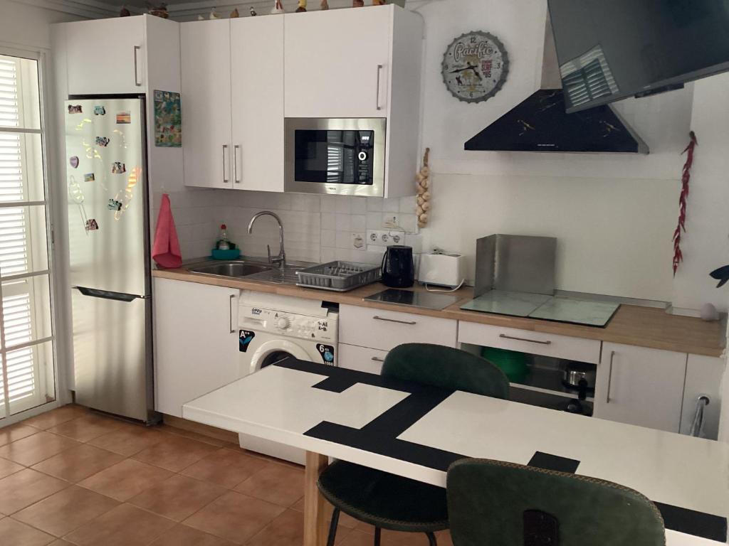 a kitchen with white cabinets and a table with chairs at Mar&sun Casa Florida in Puerto del Carmen