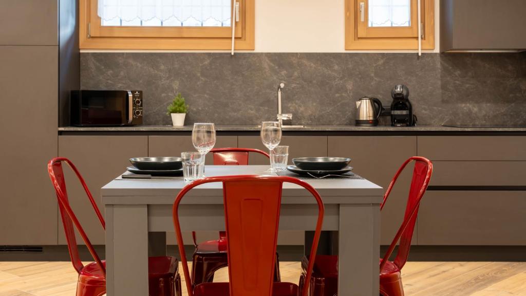 una cocina con una mesa con sillas rojas y copas de vino en Italianway - Trento 2, en Bormio