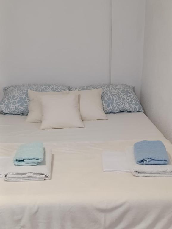ein weißes Bett mit Kissen und Handtüchern darauf in der Unterkunft Apartman Kepić in Sirova Katalena