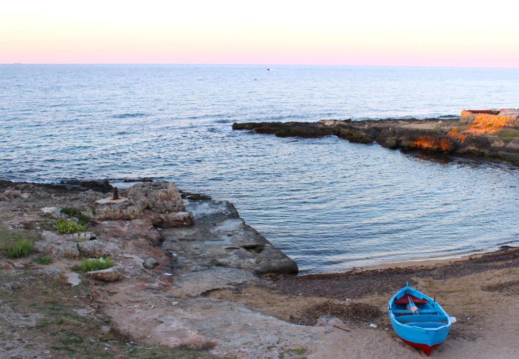 a blue boat sitting on the beach near the water at Il Principe del mare B&B in Savelletri di Fasano