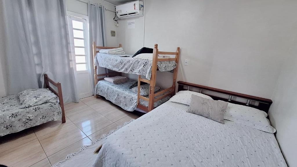 ein Schlafzimmer mit zwei Einzelbetten und einem Fenster in der Unterkunft KITNET S2 em TORRES-RS - Na mais bela praia Gaúcha - Cozinha - Banheiro - Ar condicionado - TV smart 32' - Wi-Fi - Estacionamento - Anfitriã Superhost no BnB in Torres