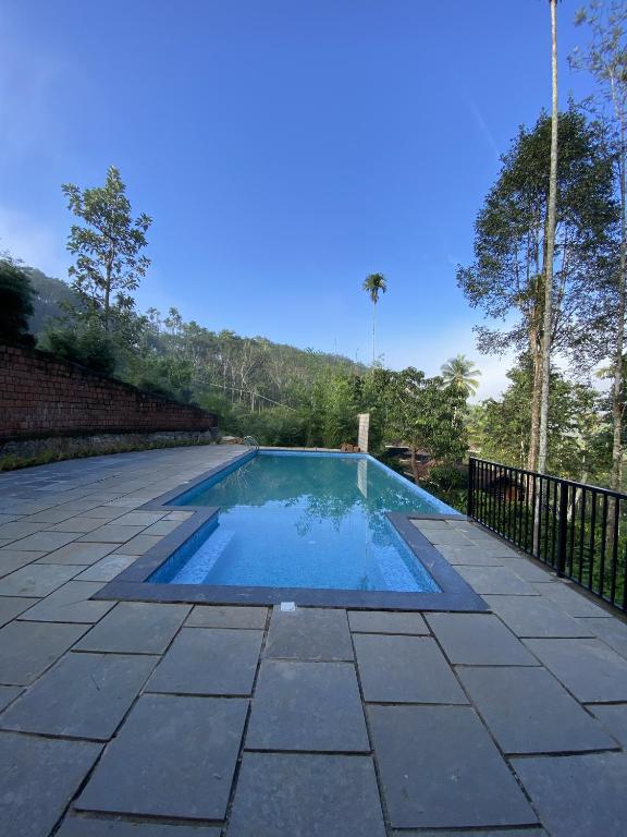 a swimming pool with blue water on a patio at Skyleaf Resort in Meenangadi