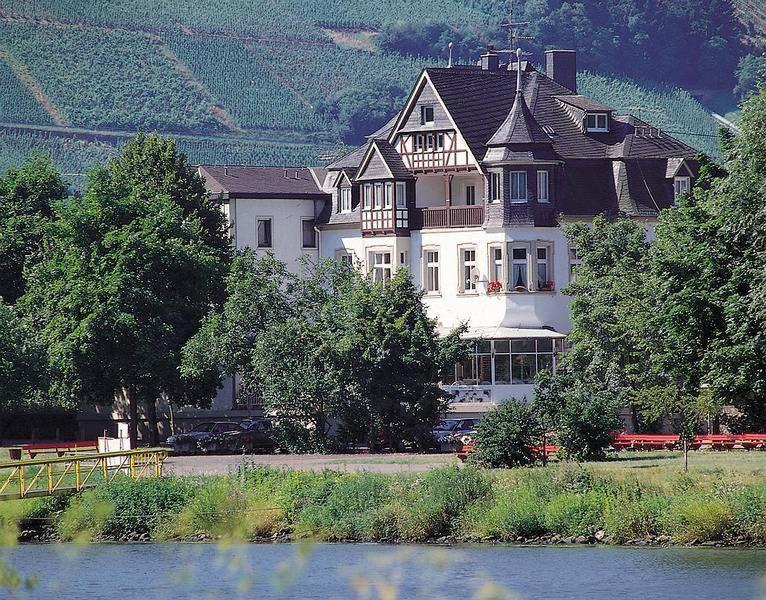 ein großes weißes Haus auf der Seite eines Flusses in der Unterkunft Hotel Krone Riesling in Trittenheim