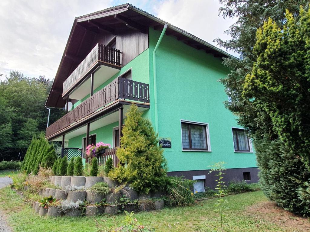 une maison verte avec un balcon au-dessus dans l'établissement Ferienhaus Erika, à Zorge