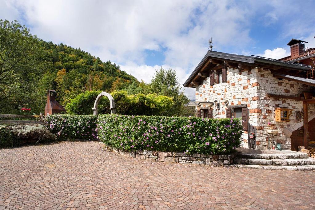 un bâtiment en pierre avec une haie à côté d'une maison dans l'établissement Baita Chalet Alabama, à Rocca