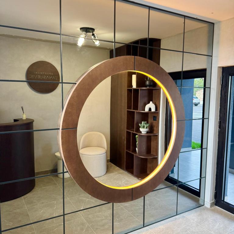 een ronde spiegel aan een muur in een kamer bij Apartmani Tanasijević 