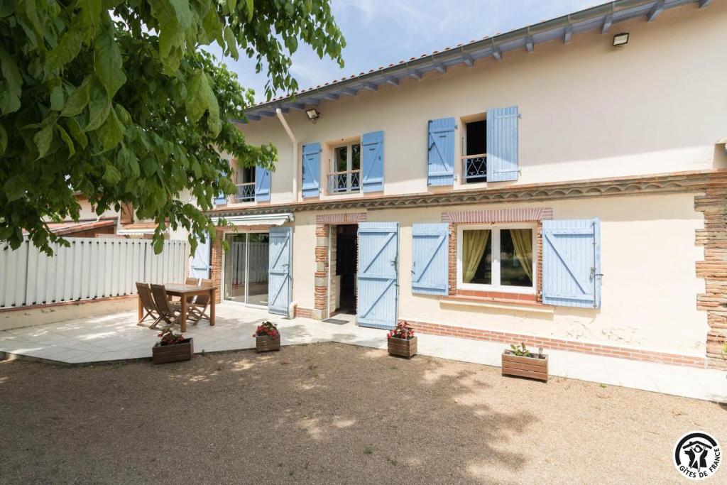 a house with blue windows and a table in the courtyard at En savanac in Albiac