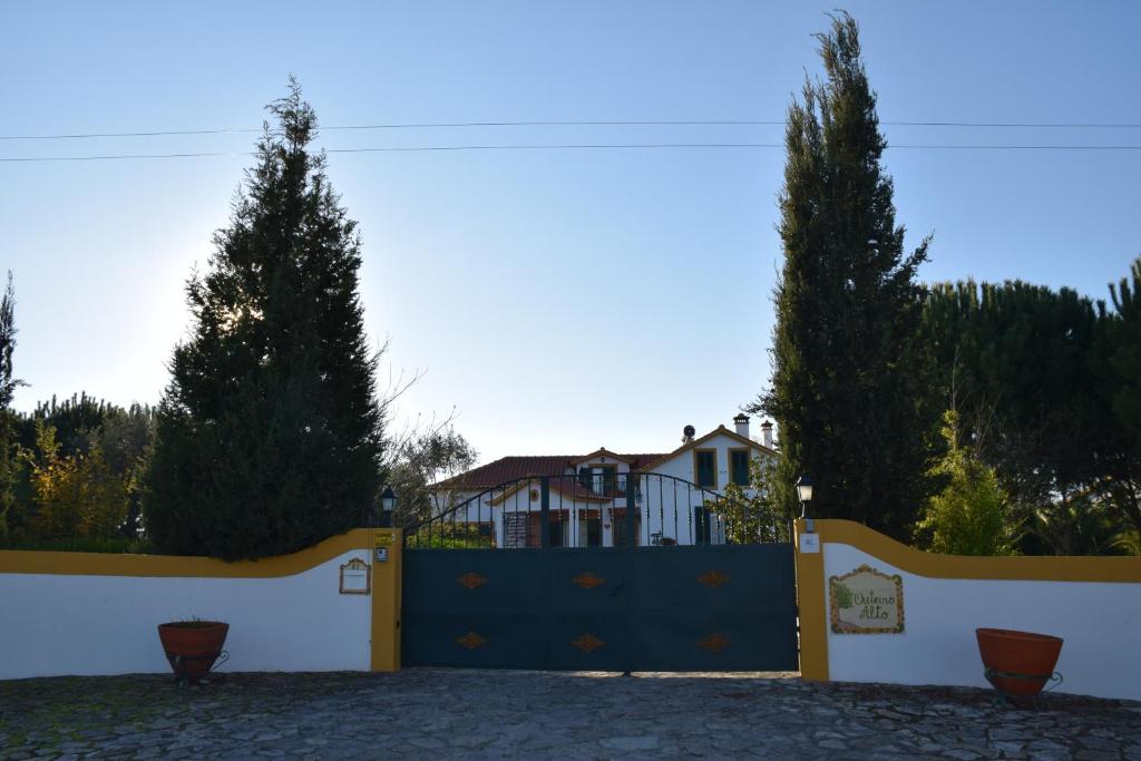 a blue gate with two trees in front of a house at Quinta do Outeiro Alto in Constância