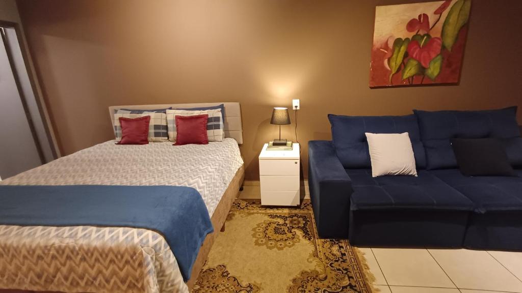 une chambre avec deux lits et un canapé bleu dans l'établissement Studio Barreto Leme Ap72, à Campinas