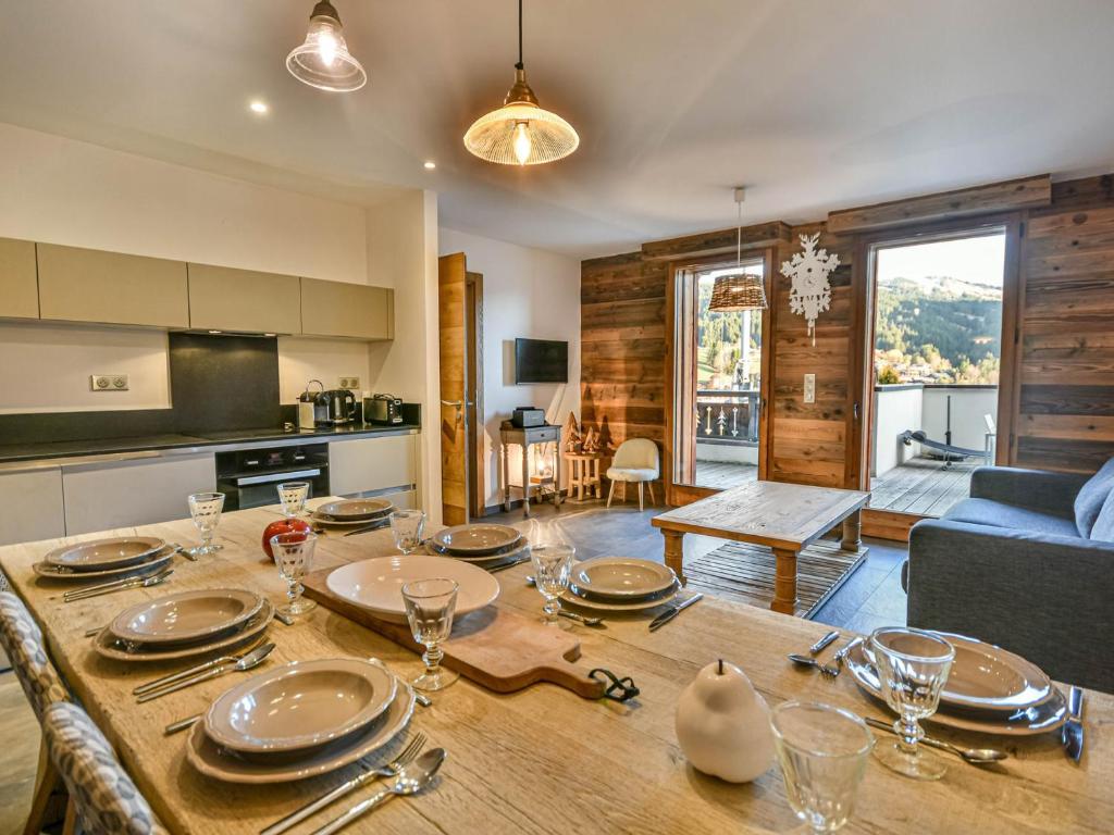 a kitchen and living room with a wooden table with plates at Chalet 3 chambres - Sauna et salle de sport - 8 pers - FR-1-685-91 in Les Gets