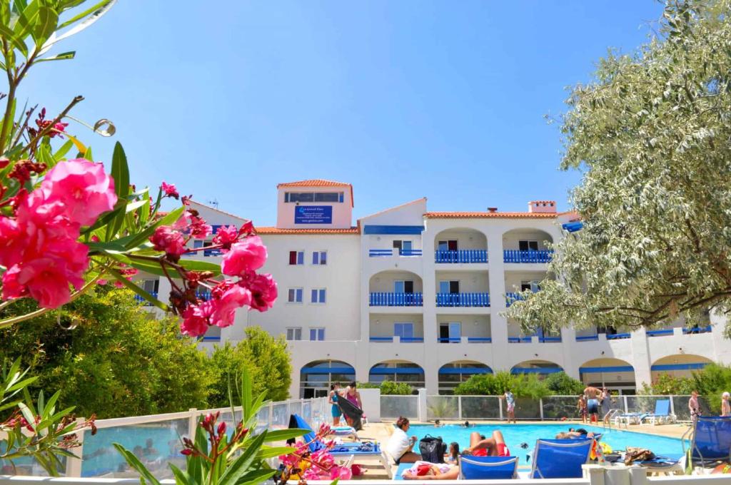 a large white building with a pool and pink flowers at Notre location au Barcarès in Le Barcarès