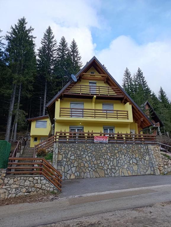 a yellow house on top of a stone wall at Divan Vlašić in Šišava