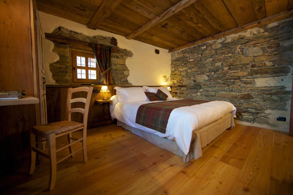 een slaapkamer met een bed en een stenen muur bij A barma drola in Brusson