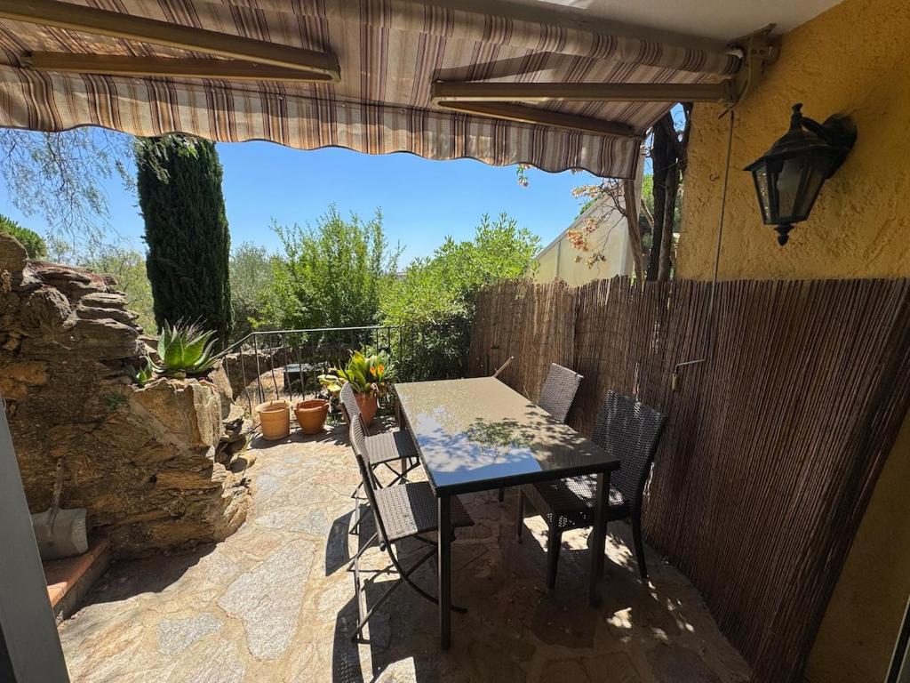 eine Terrasse mit Tisch und Stühlen und einem Zaun in der Unterkunft Cozy apartment in Bormes-les-Mimosas