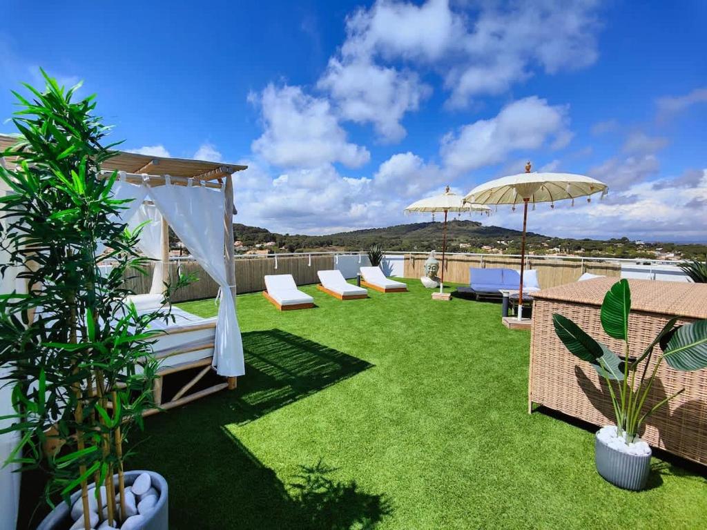 阿格德角L'horizon T4 vue mer rooftop balcon garages的带躺椅、遮阳伞和草坪的露台