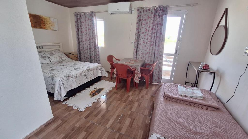 ein Schlafzimmer mit einem Bett und einem Tisch und Stühlen in der Unterkunft KITNET S4 em TORRES-RS - Confortável com cama casal box, cama de solteiro bicama, televisão, geladeira, micro-ondas, chaleira elétrica, ar-condicionado split - Anfitriã Superhost no BnB in Torres