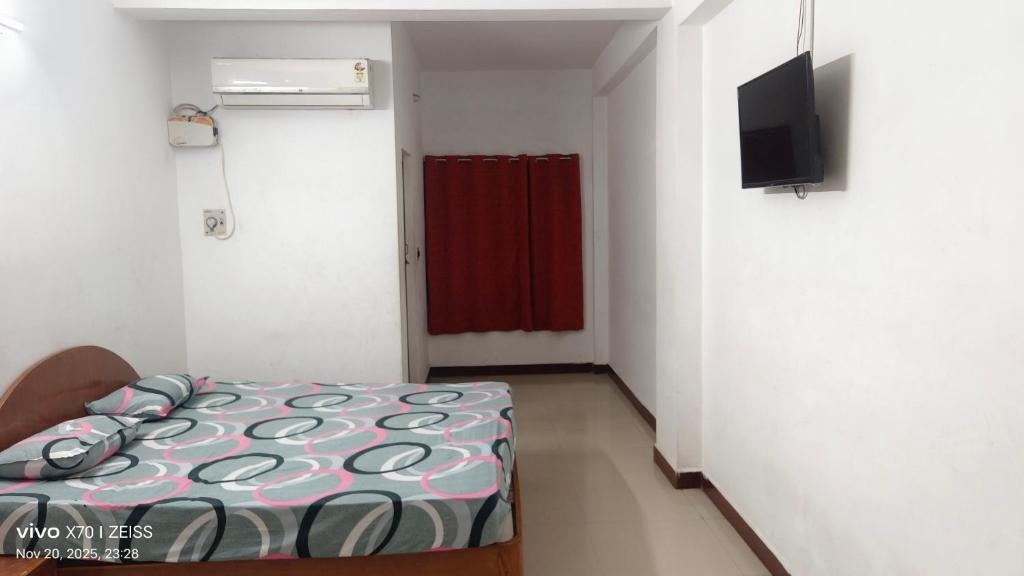 Una pequeña habitación con una cama y un televisor. en Suriya Inn, en Tiruchchirāppalli