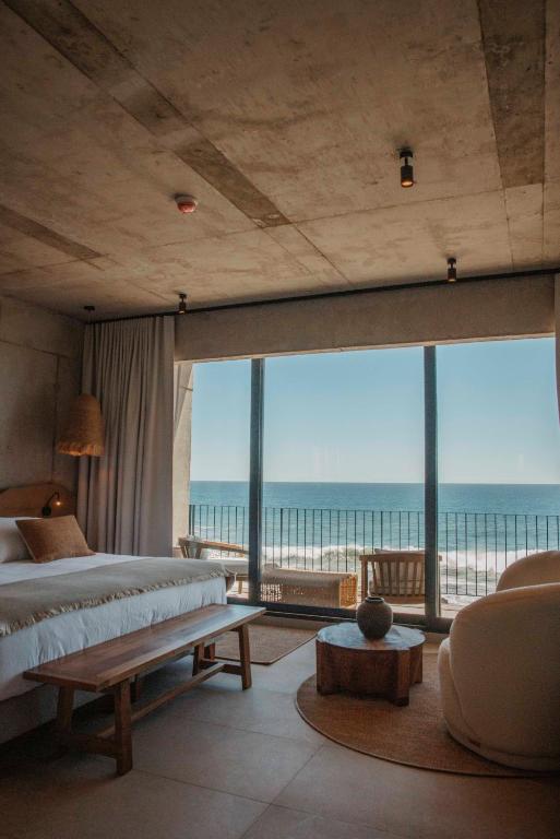 a bedroom with a bed and a view of the ocean at Hotel Maró in Pichilemu