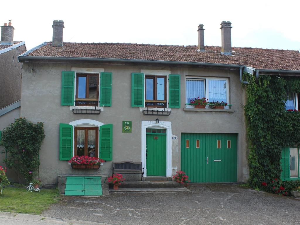 a green and white house with green shutters at Gîte confortable avec terrasse et jardin, près de Baccarat, idéal pour nature et détente - FR-1-584-51 in Reherrey