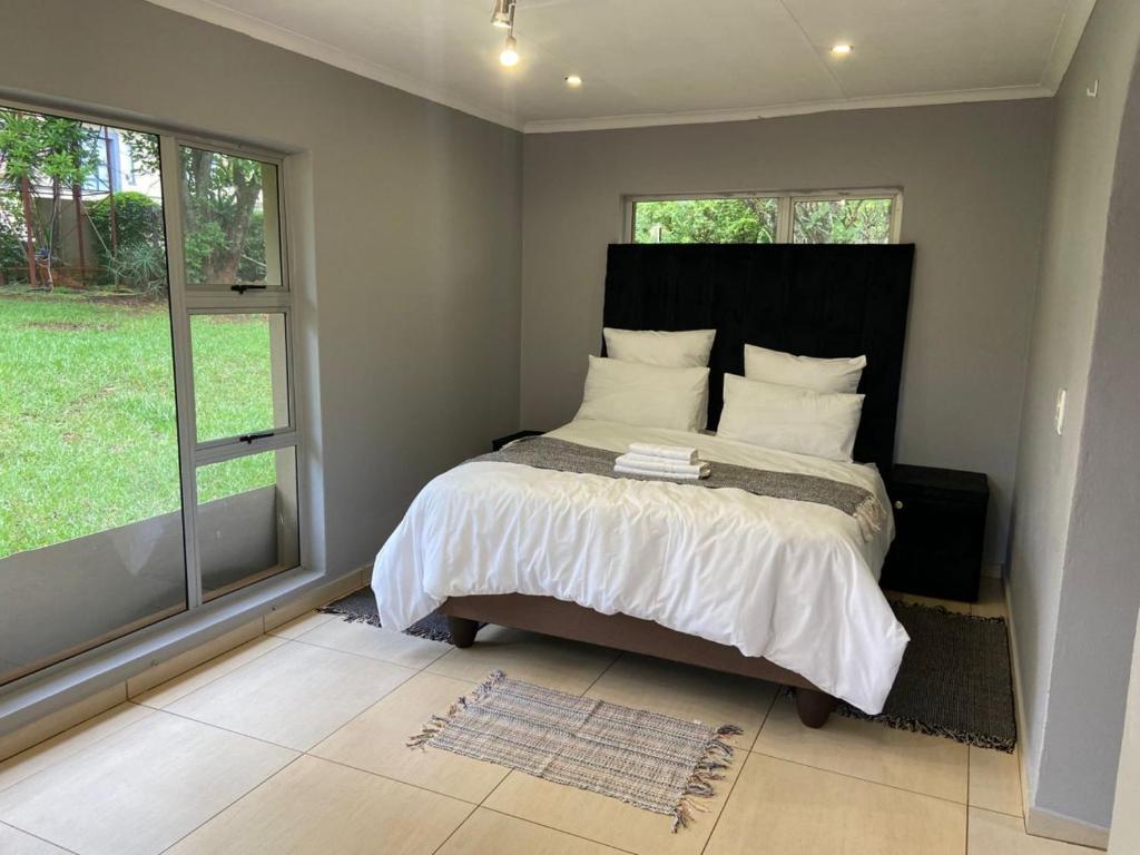 Un dormitorio con una cama y dos ventanas en Hazel Nest Ezulwini, en Ezulwini