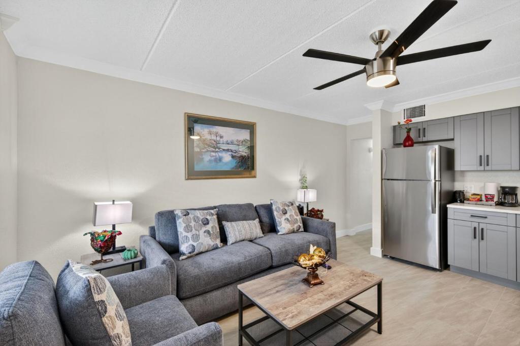 a living room with a blue couch and a refrigerator at Sunset Beach Suites Unit 3 in St. Pete Beach