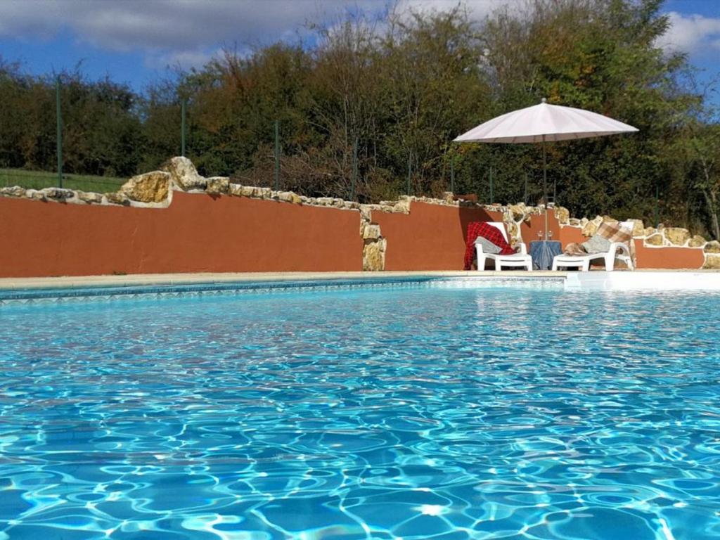 ein Swimmingpool mit Stühlen und einem Sonnenschirm in der Unterkunft Ancien moulin avec piscine, terrasse, jardin privatif et petite île - près des étangs de la Brenne - FR-1-591-159 in Prissac
