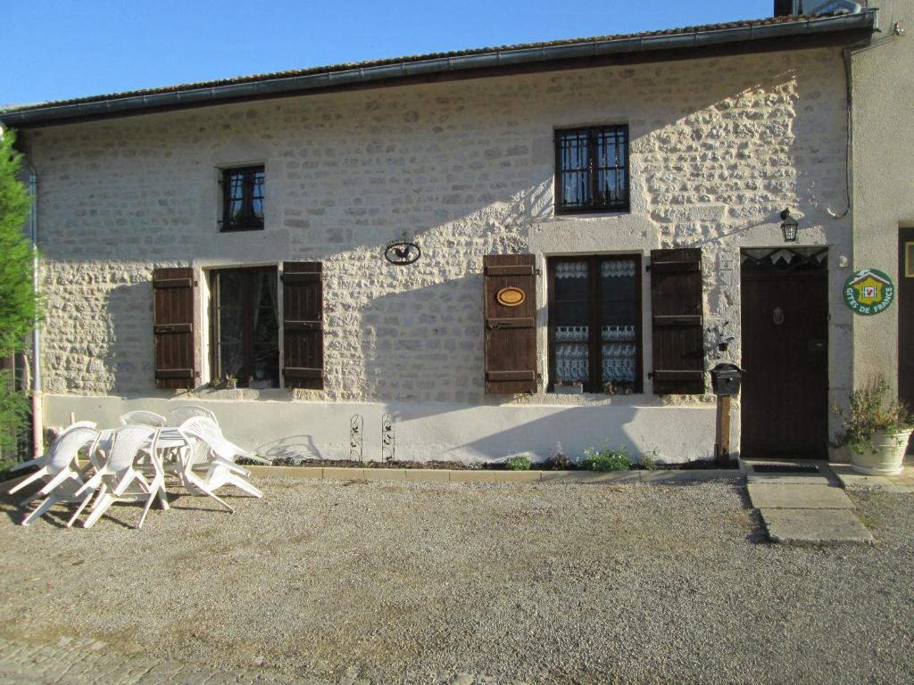 eine Gruppe weißer Stühle vor einem Gebäude in der Unterkunft Maison cosy avec terrasse, 3 chambres, wifi, animaux acceptés, idéal pour familles en Meuse - FR-1-585-2 in Bréhéville