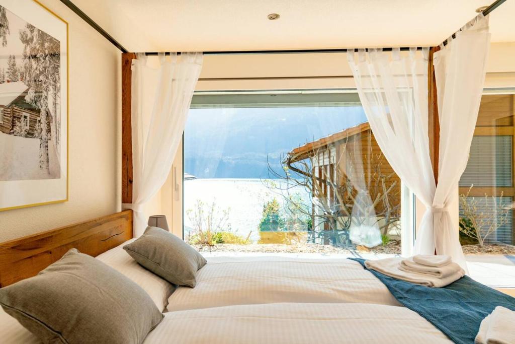 una camera da letto con un letto e una grande finestra di Luxury Lakeview Chalet with AC & SPA near Interlaken a Niederried