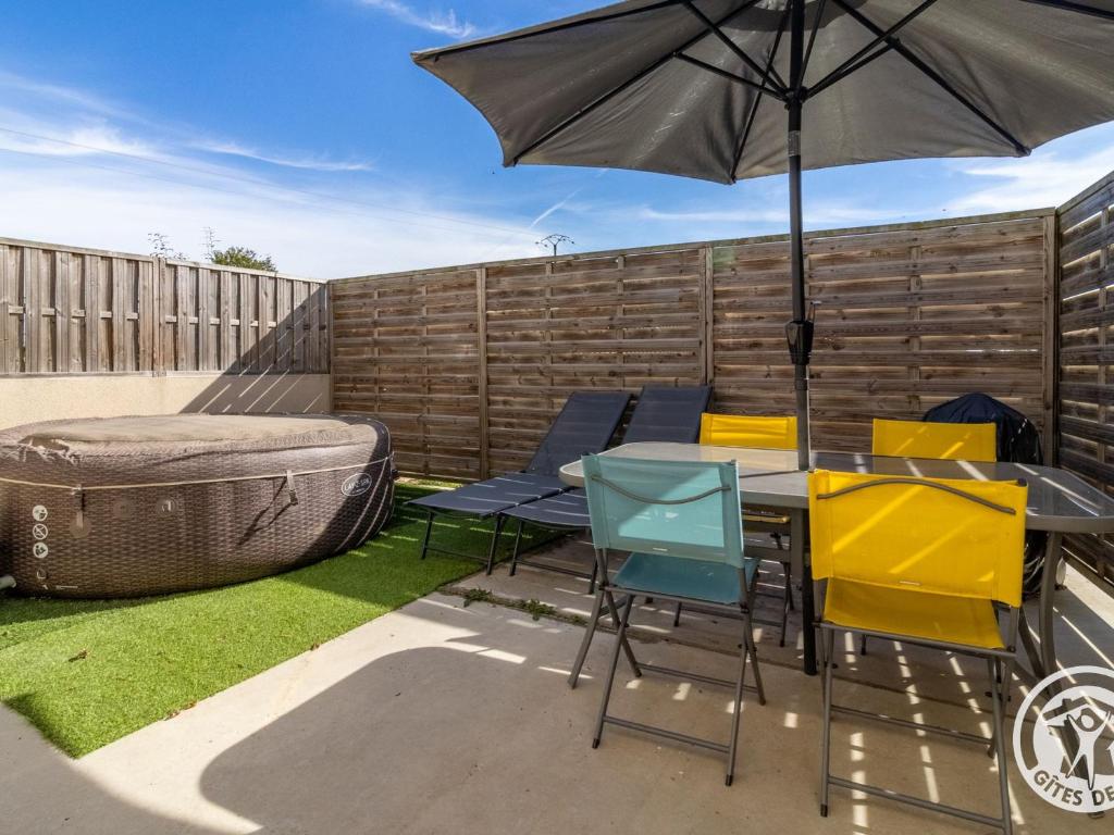 a patio with a table and chairs and an umbrella at Gîte cosy avec spa privatif, terrasse et parking, au cœur des vignobles du Layon, idéal pour couples. - FR-1-622-21 in La Viardière
