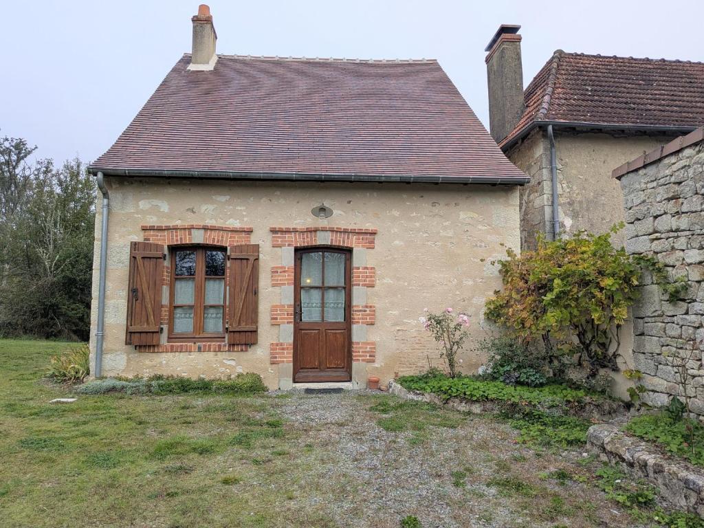 Cette petite maison dispose d'une porte et de fenêtres marron. dans l'établissement Maison de Caractère Rénovée avec Jardin, Terrasse, et Proche du Château Guillaume - FR-1-591-131, à Lignac