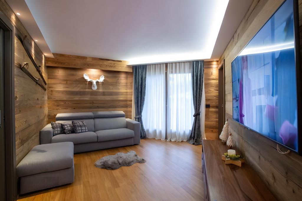 a living room with a couch and a flat screen tv at Apt Design a Campiglio 400m funivie in Madonna di Campiglio