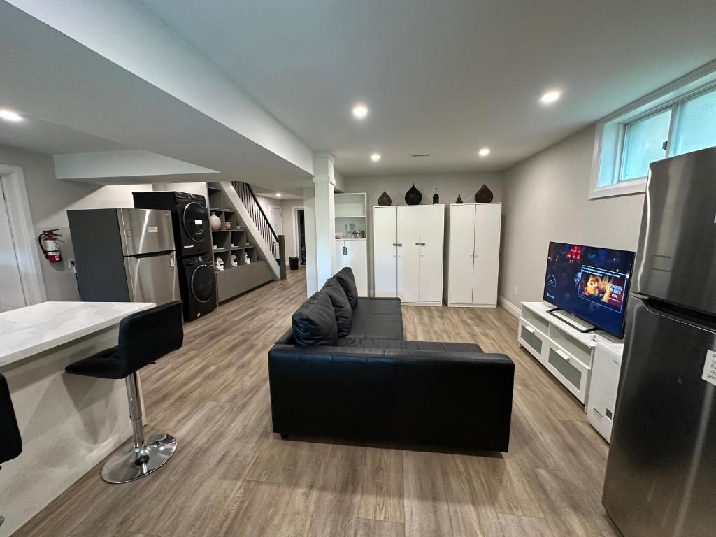 un salon avec un canapé noir et une télévision dans l'établissement 1-Bedroom 1Bathroom Entire Unit closer to Fairview Mall & Waterloo Airport, à Kitchener
