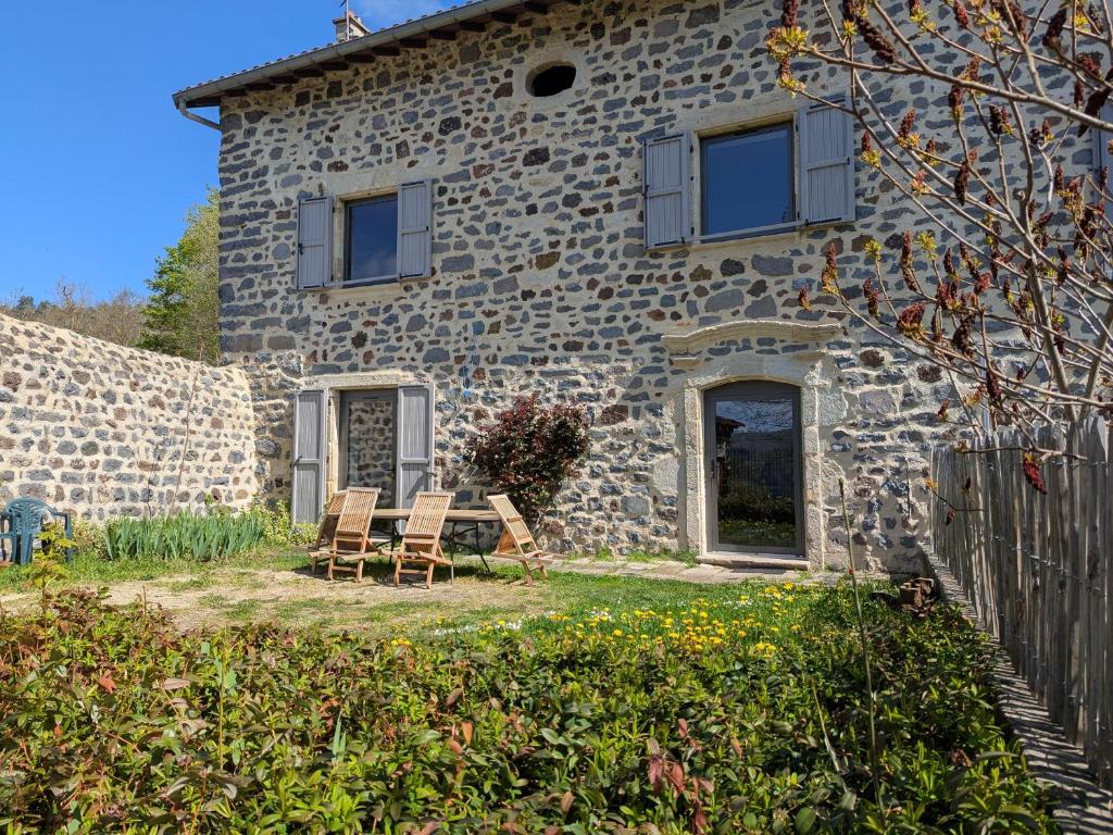 a stone house with chairs and a table in front of it at Élégante maison de maître XVIIIe, jardin clos 500m², nature, proche Puy-en-Velay, 11 pers., cosy & confort - FR-1-582-315 in Arsac-en-Velay