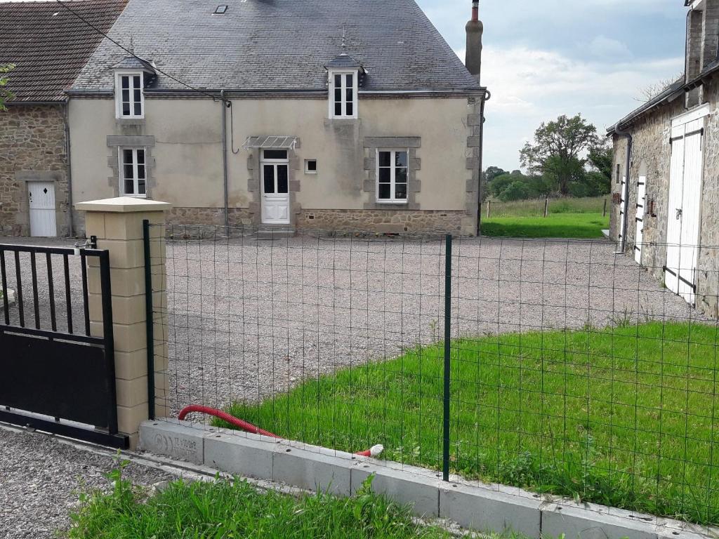 une clôture devant une vieille maison dans l'établissement Maison paisible entre Berry et Creuse avec jardin clos, terrasse et parking privé - FR-1-591-310, à Crevant