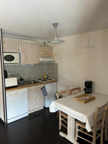 eine Küche mit einem weißen Tisch und eine Küche mit einem Tisch und Stühlen in der Unterkunft Appartement cosy Luz-St-Sauveur Ski et randonnée in Luz-Saint-Sauveur