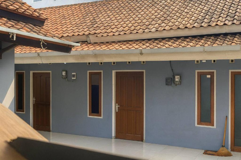 una casa azul con puertas marrones y techo rojo en Reza Kost, en Karanganyar