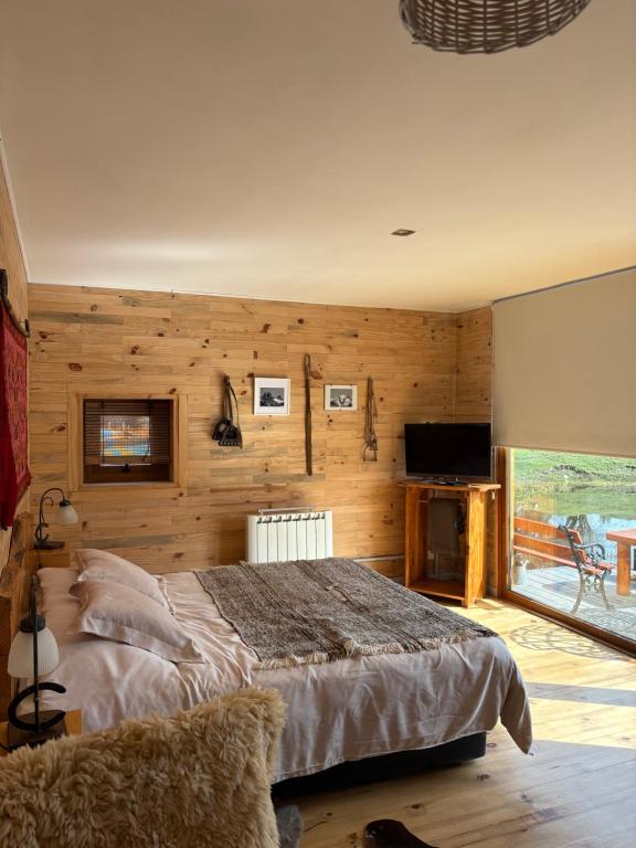 a bedroom with a large bed and a television at Wau Purul, Cabaña 2 in Cholila