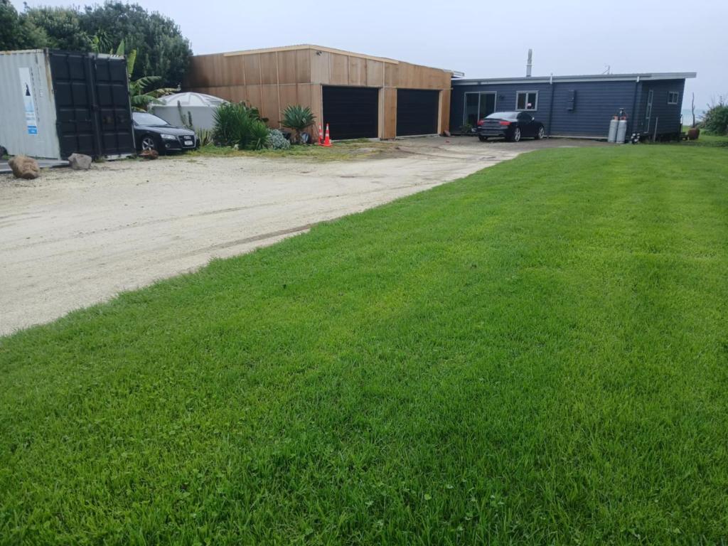 une cour avec de l'herbe verte et un bâtiment dans l'établissement Ocean Shores Warea, 
