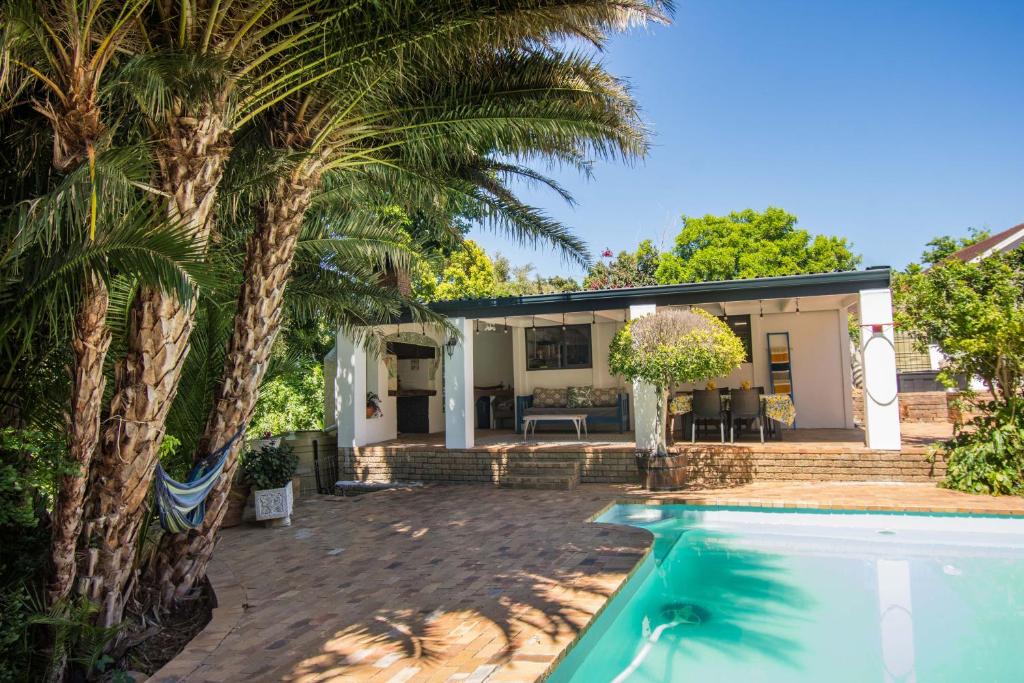 a house with a swimming pool and palm trees at Sunny Poolside Escape in Somerset West in Somerset West