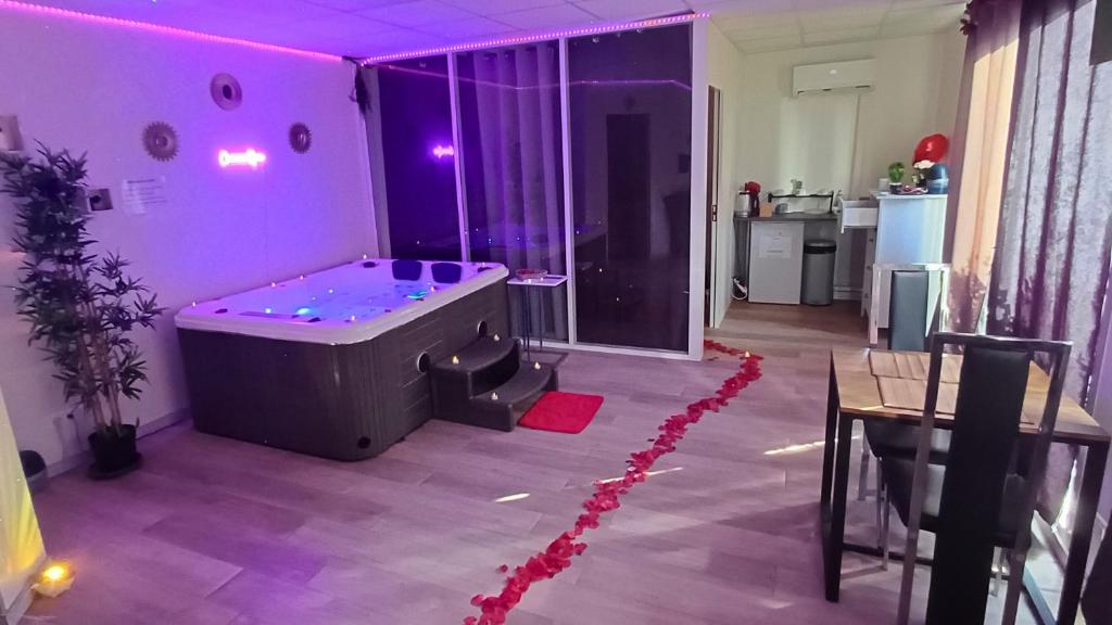 Habitación púrpura con bañera y mesa en CocoonSPA LoveRoom Jacuzzi, en Toulouse