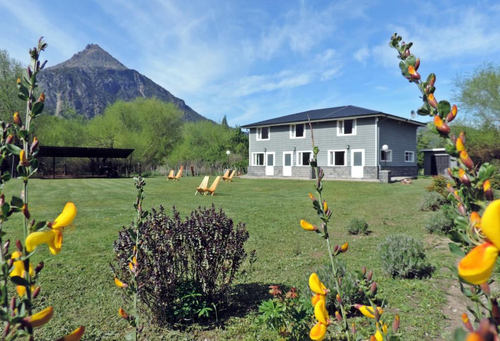 a house in a field with a mountain in the background at Río Epuyén Aparts in El Hoyo