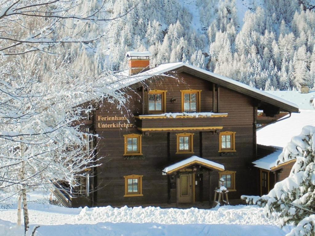 una cabaña de troncos en la nieve con nieve en Ferienhaus Unterkircher-Wallner, en Heiligenblut