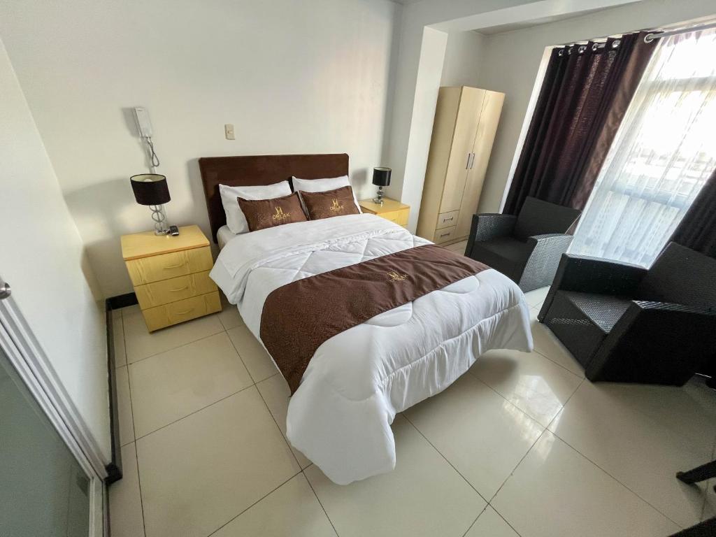 a bedroom with a large bed and a chair at Hotel Orlak in Huancayo