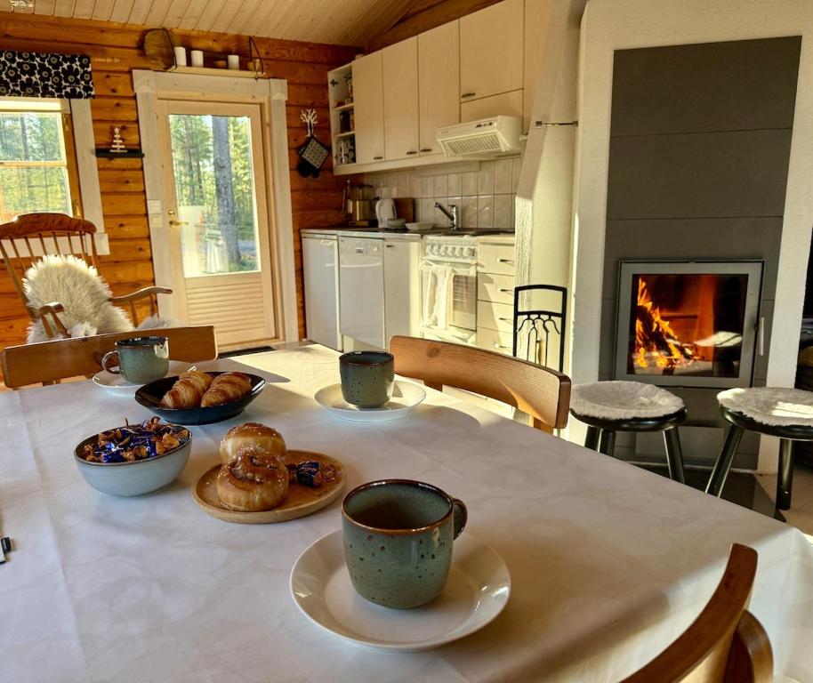 ein Tisch mit Tassen und Teller mit Essen drauf in der Unterkunft Kantolammen mökki 66m2, kylpypalju ja puusauna in Kuusamo