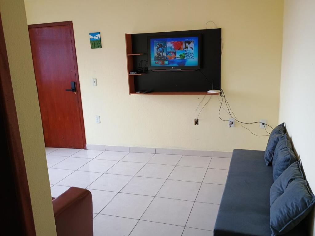 a living room with a couch and a flat screen tv at Ap 2 quartos aconchegante com ar-condicionado in Viçosa