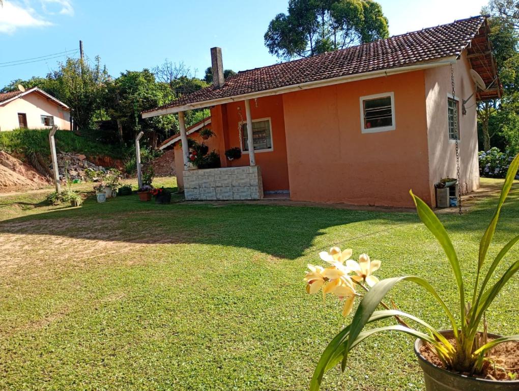 ein kleines orangefarbenes Haus mit einer Pflanze im Garten in der Unterkunft Morada Jaguary in Camanducaia