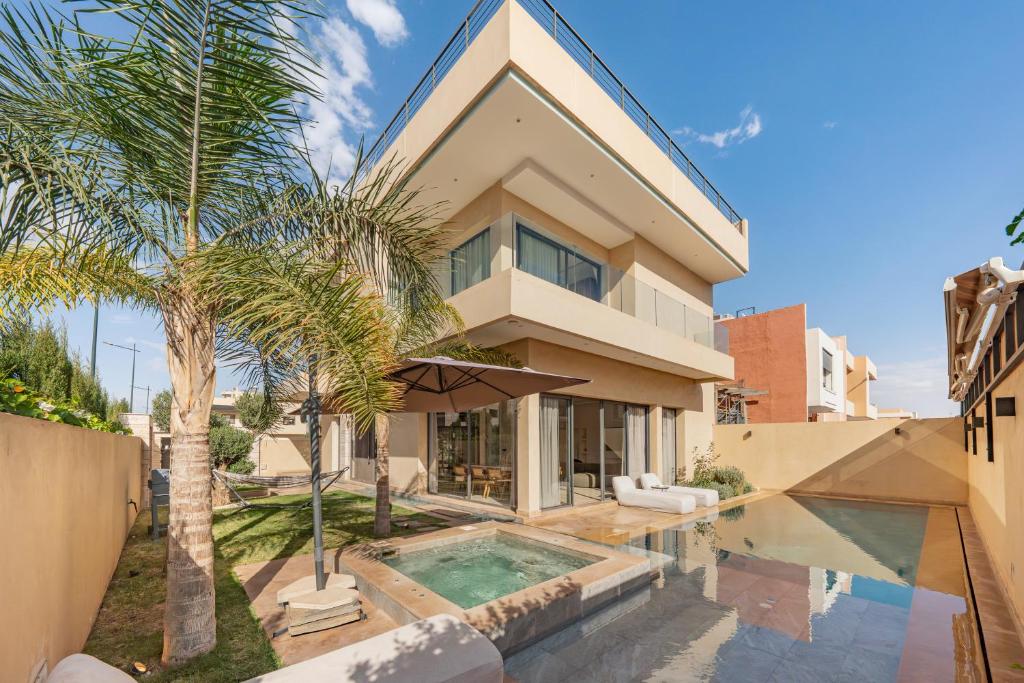 ein Haus mit einem Pool und Palmen in der Unterkunft Villa Tolède by TheCasaEdition in Marrakesch