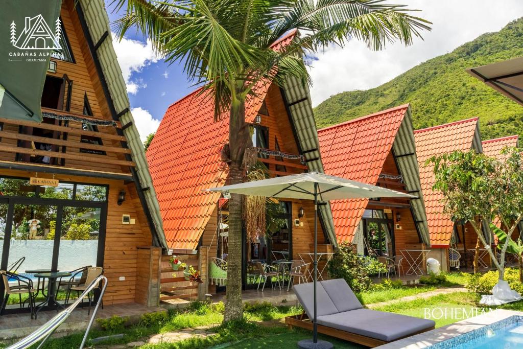ein Haus mit einer Palme und einem Regenschirm in der Unterkunft Cabañas Alpinas en Oxapampa in Oxapampa